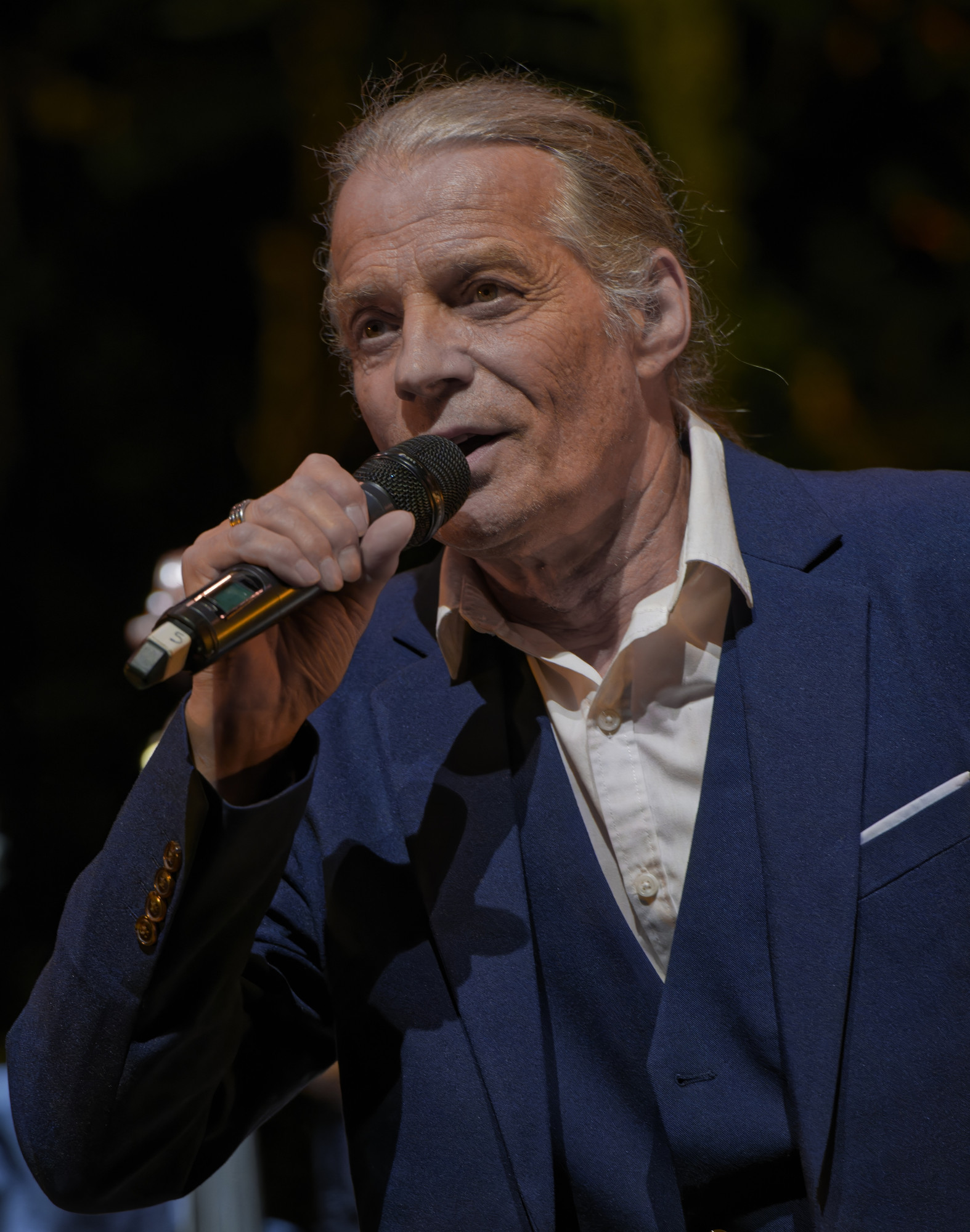 Tom Torel chante au micro en costume bleu